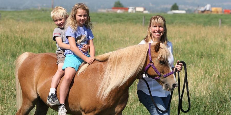 Image of a mom with kids riding a horse
