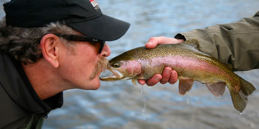 image of man kissing a rainbow trout