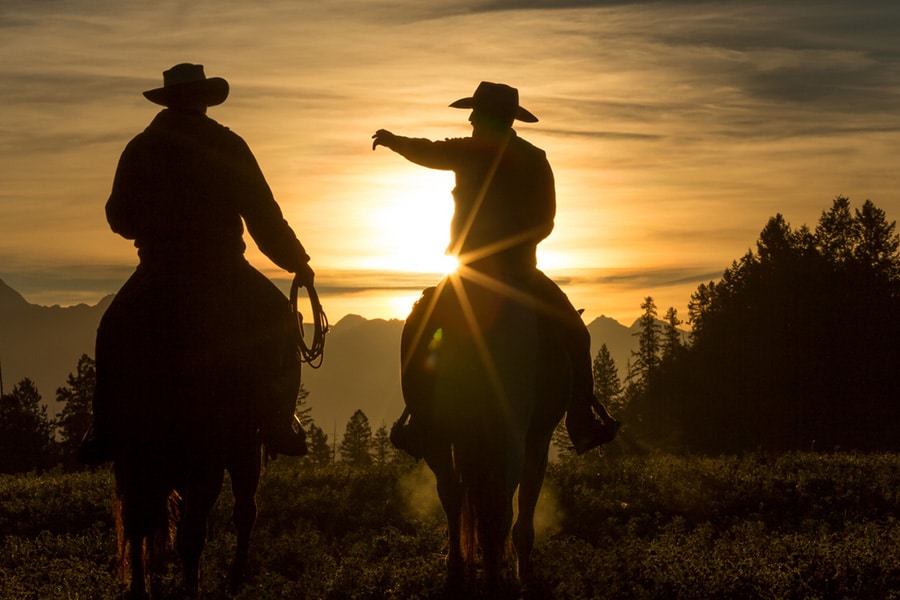 image of two cowboys riding into the sunset